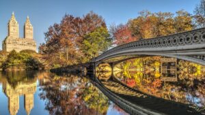 Close up of Bow Bridge over water with skyline with Central Park in background in NYC, New York, USA